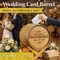 Guest placing a card into a personalized oak wedding barrel card holder at a rustic winery wedding reception.